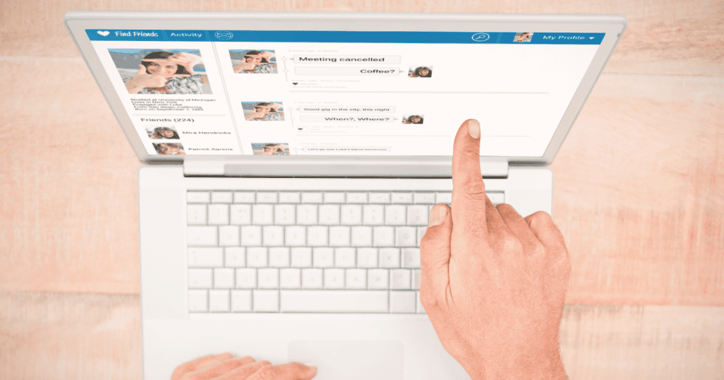 A top-down perspective of a person pointing their finger at a social media feed on a laptop screen, highlighting the process of monitoring and refining digital interactions.